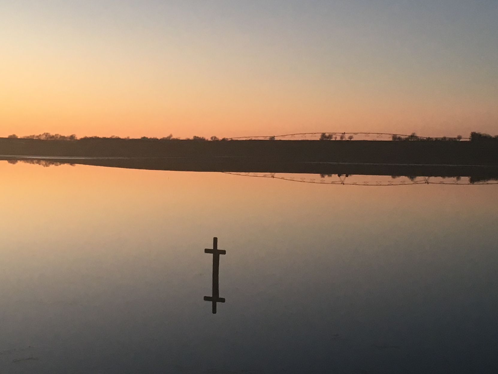 Cross in water at sunset